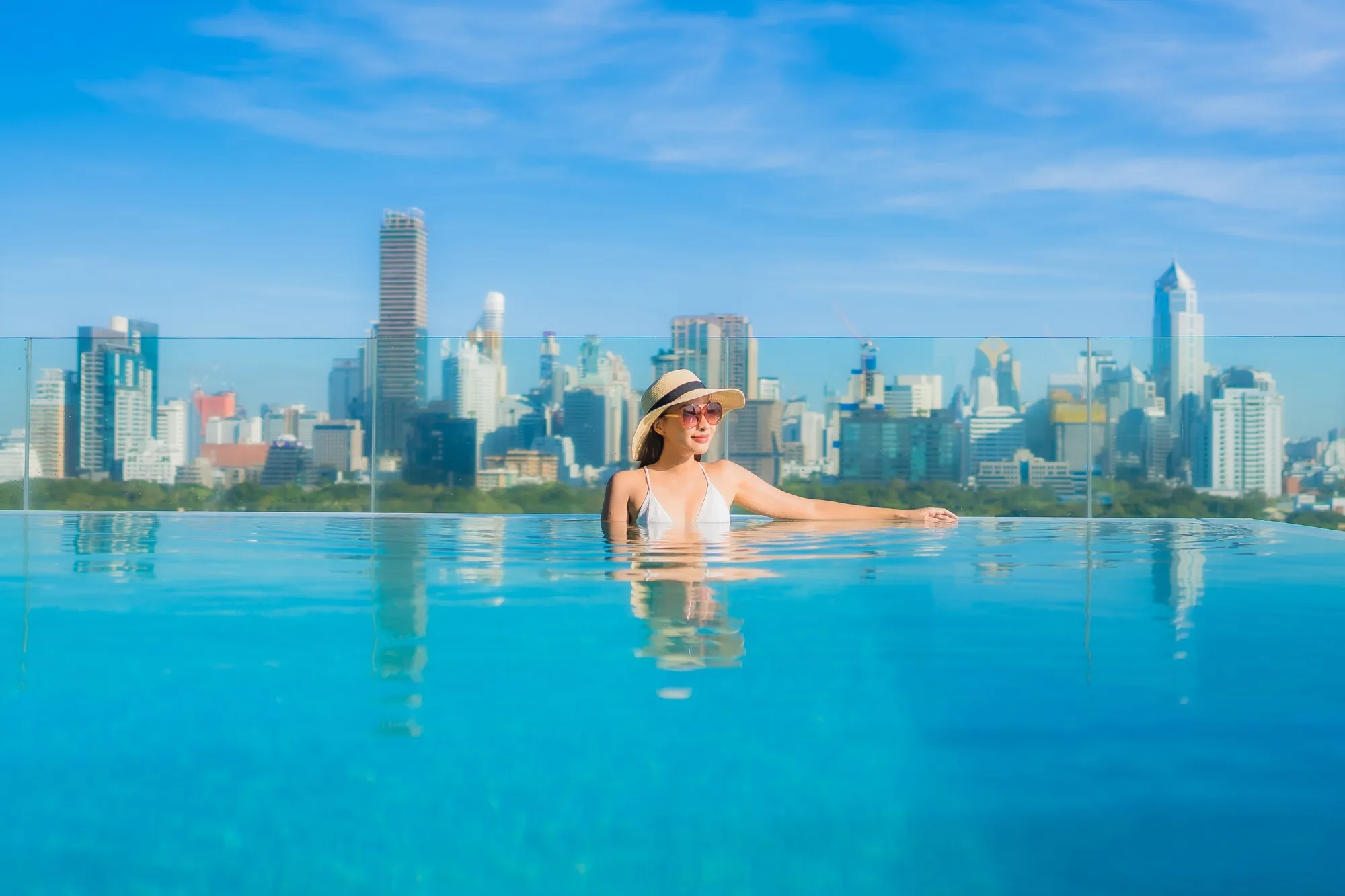Woman in an infinity pool overlooking a city skyline